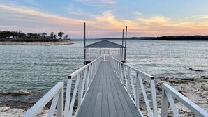A wooden pier leading to a covered area by a calm body of water with a clear sky. - Secluded Lakeside RV Experience (Bridgeport)