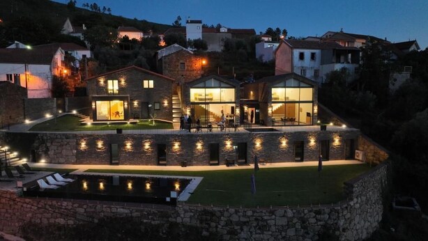 A modern villa with a stone facade, large glass windows, and a swimming pool. - Empreendimento Serra (Covilhã)