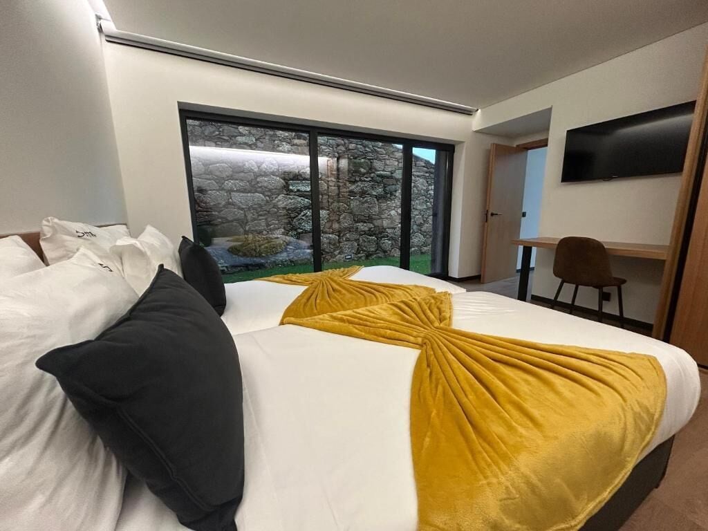 Habitación de hotel con una cama grande, un escritorio, una silla y televisión en la pared.