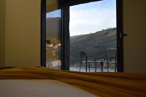 Una habitación con una cama, una colcha amarilla y vistas a un balcón con sillas y una mesa.