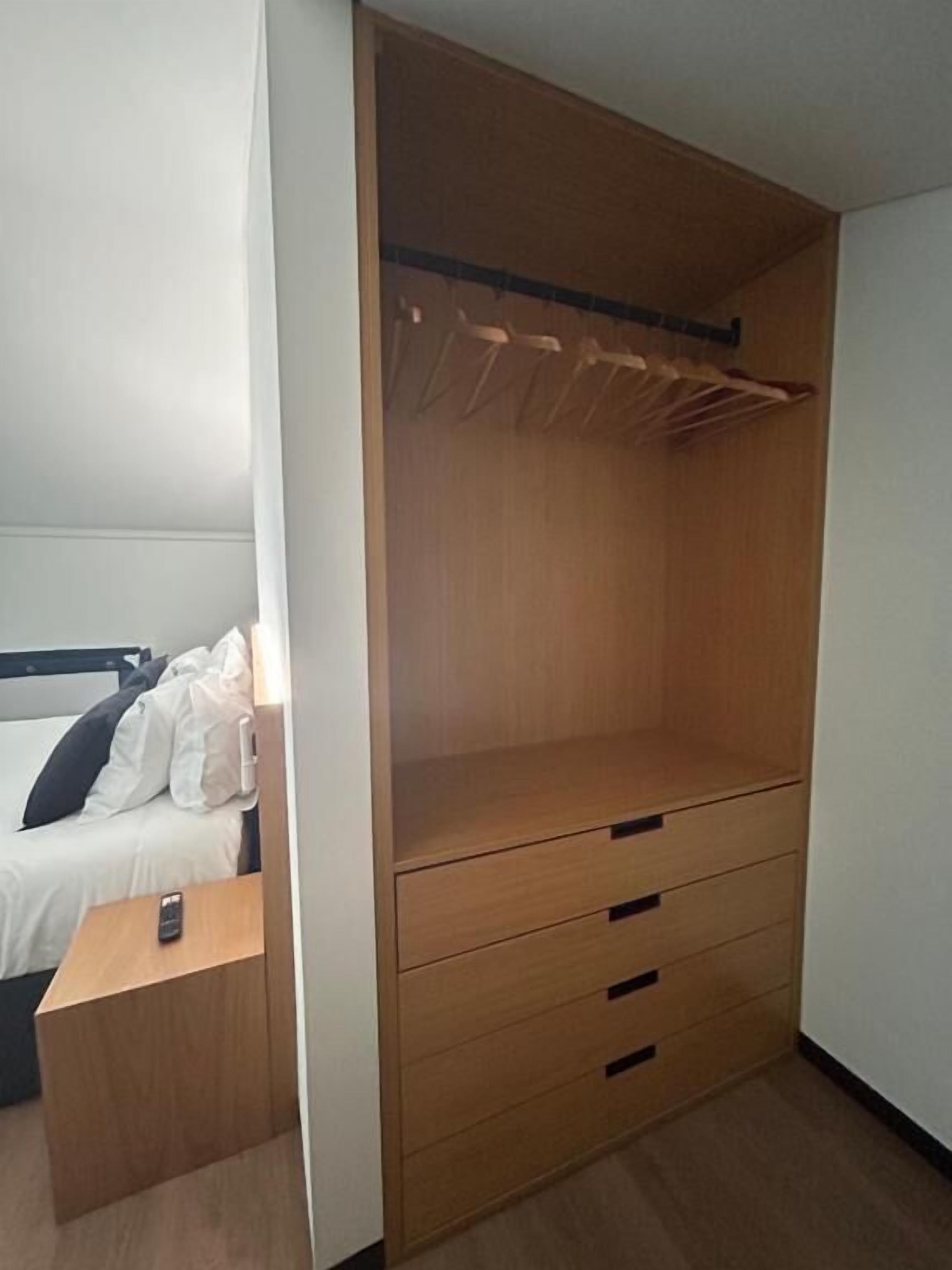 Un dormitorio con cama, un armario de madera con cajones y una mesita de noche.