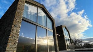 A modern building with large glass windows and stone walls. - Empreendimento Serra (Covilhã)
