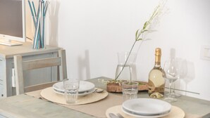A dining table set with plates, glasses, and a bottle of champagne.