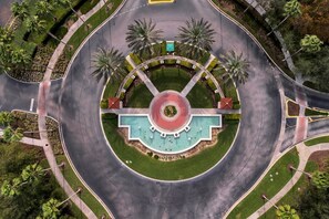 An aerial view of a roundabout with a central fountain, surrounded by palm trees and greenery. - Spacious 5-bedroom villa, 3 mi. To Disney, with WiFi, private pool (Kissimmee)