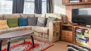 Een gezellige woonkamer met een bank, een televisie en een kast met spelletjes.