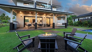 A modern house with a covered patio, outdoor seating, and a fire pit. - Modern Kauaʻi Luxury Home With Ohana, Pool, and Spa in Kukuiʻula (Koloa)