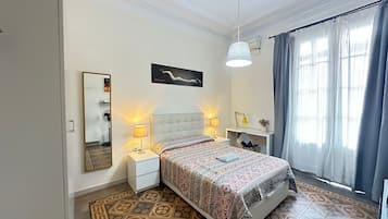 Un dormitorio con cama, mesitas de noche, escritorio y silla.