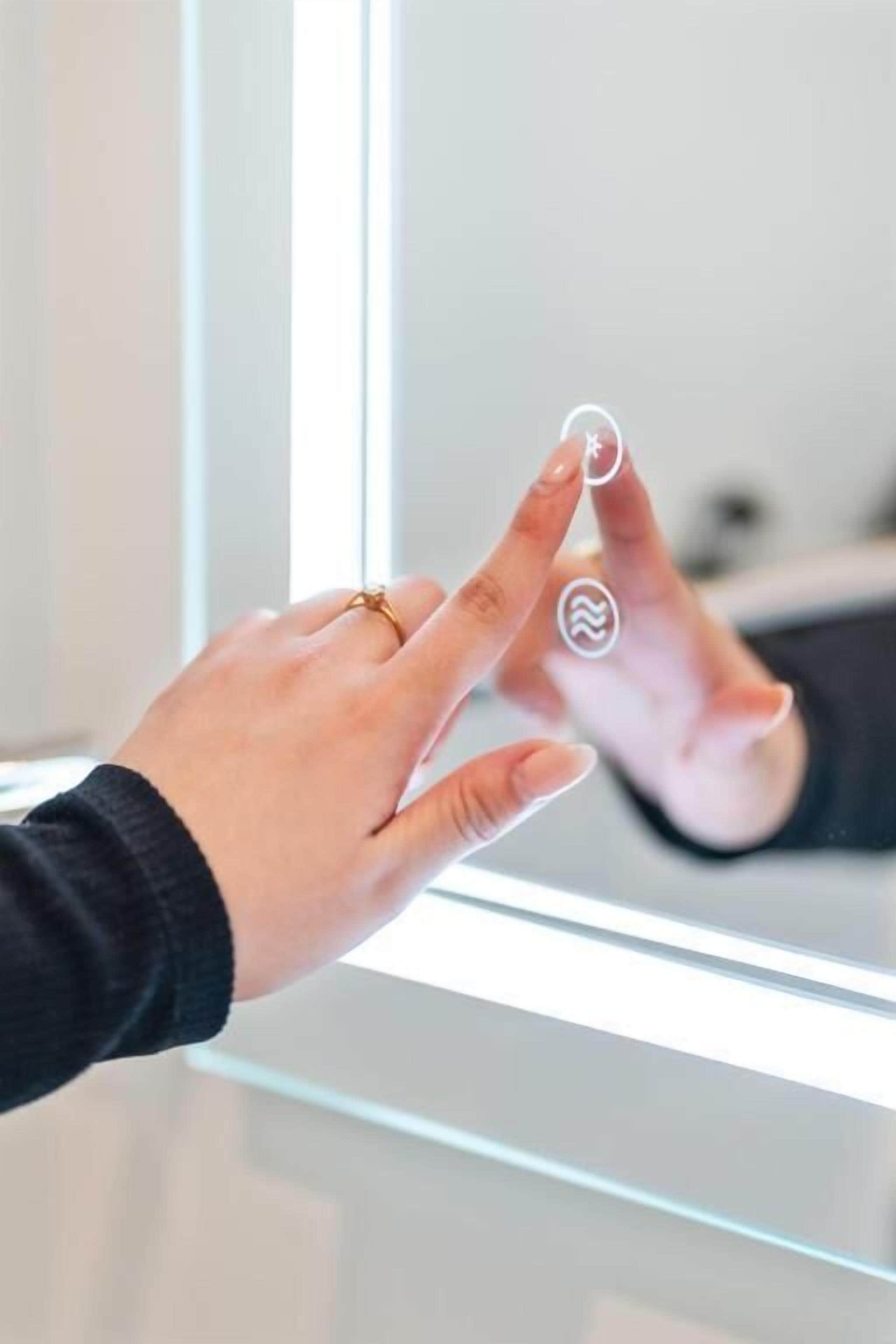 A hand interacting with a touch-sensitive interface on a glass surface.