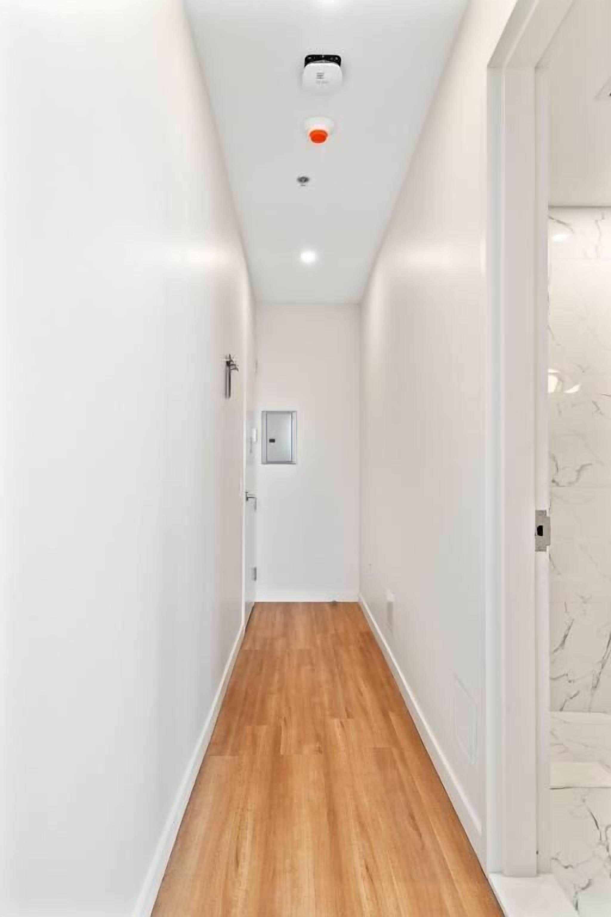 Un pasillo estrecho con suelo de madera y paredes blancas.