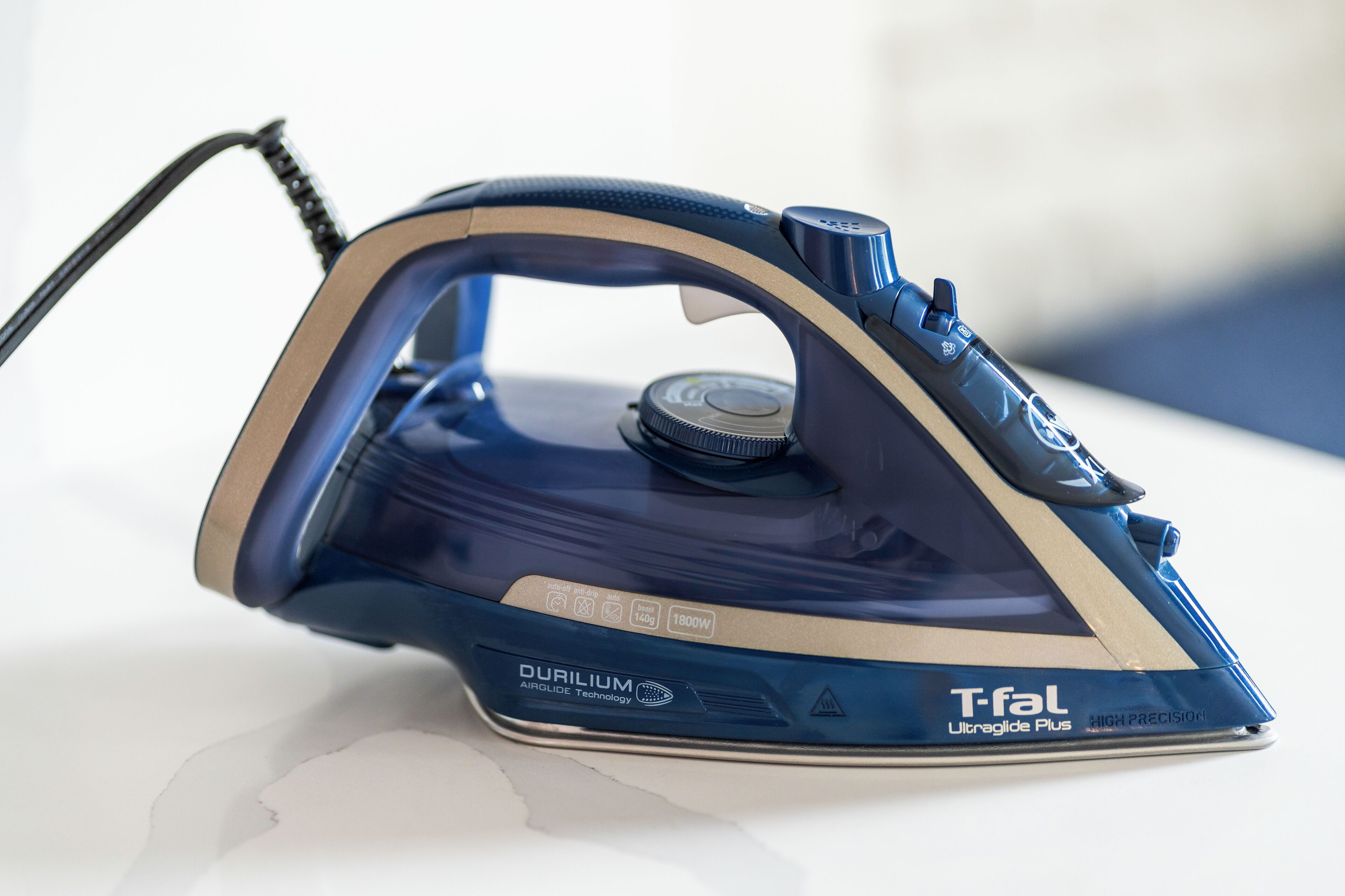 Una plancha T-fal azul y beige con panel de control y cable.