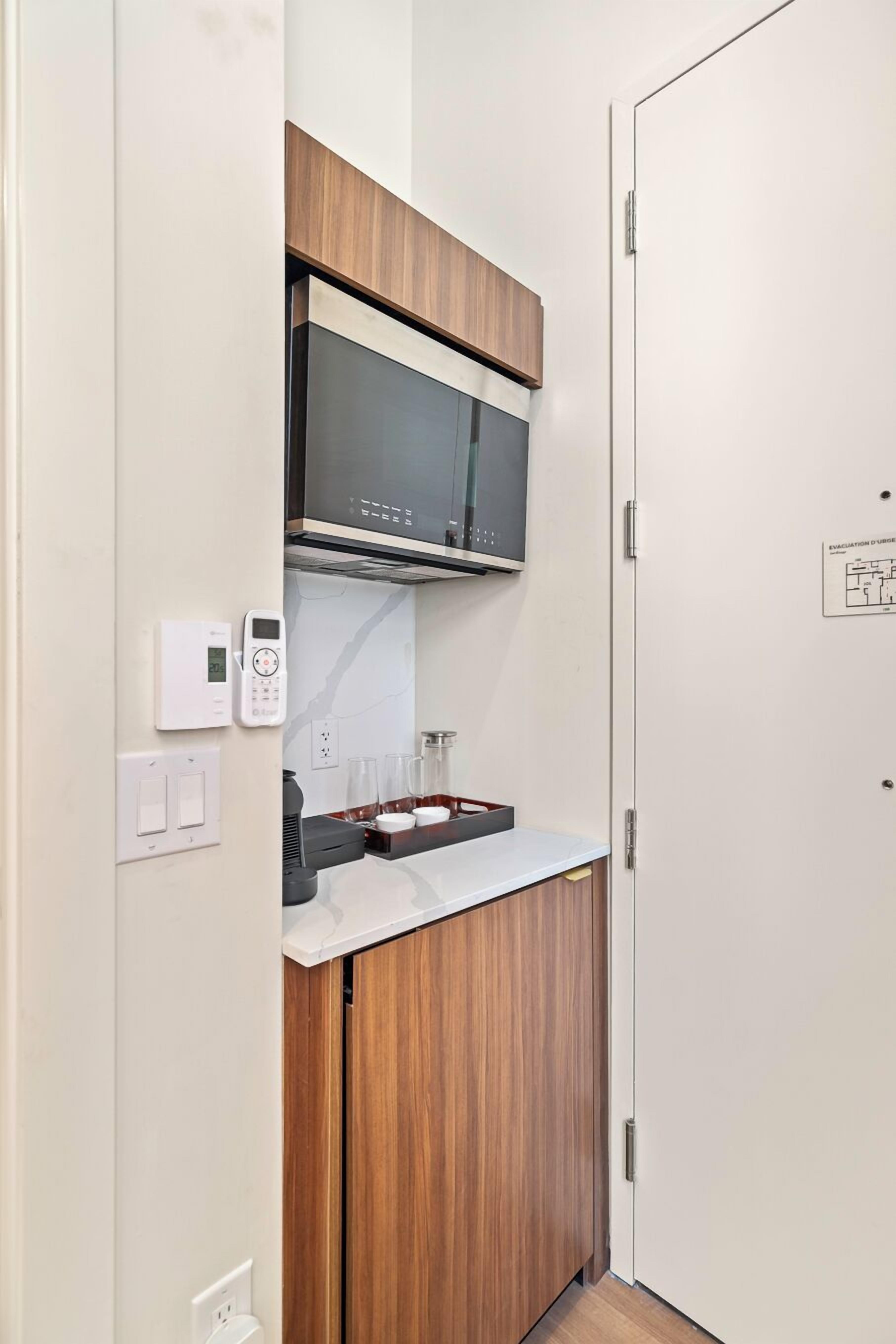Une petite cuisine équipée comprenant un four à micro-ondes, un petit plan de travail et un meuble en bois.