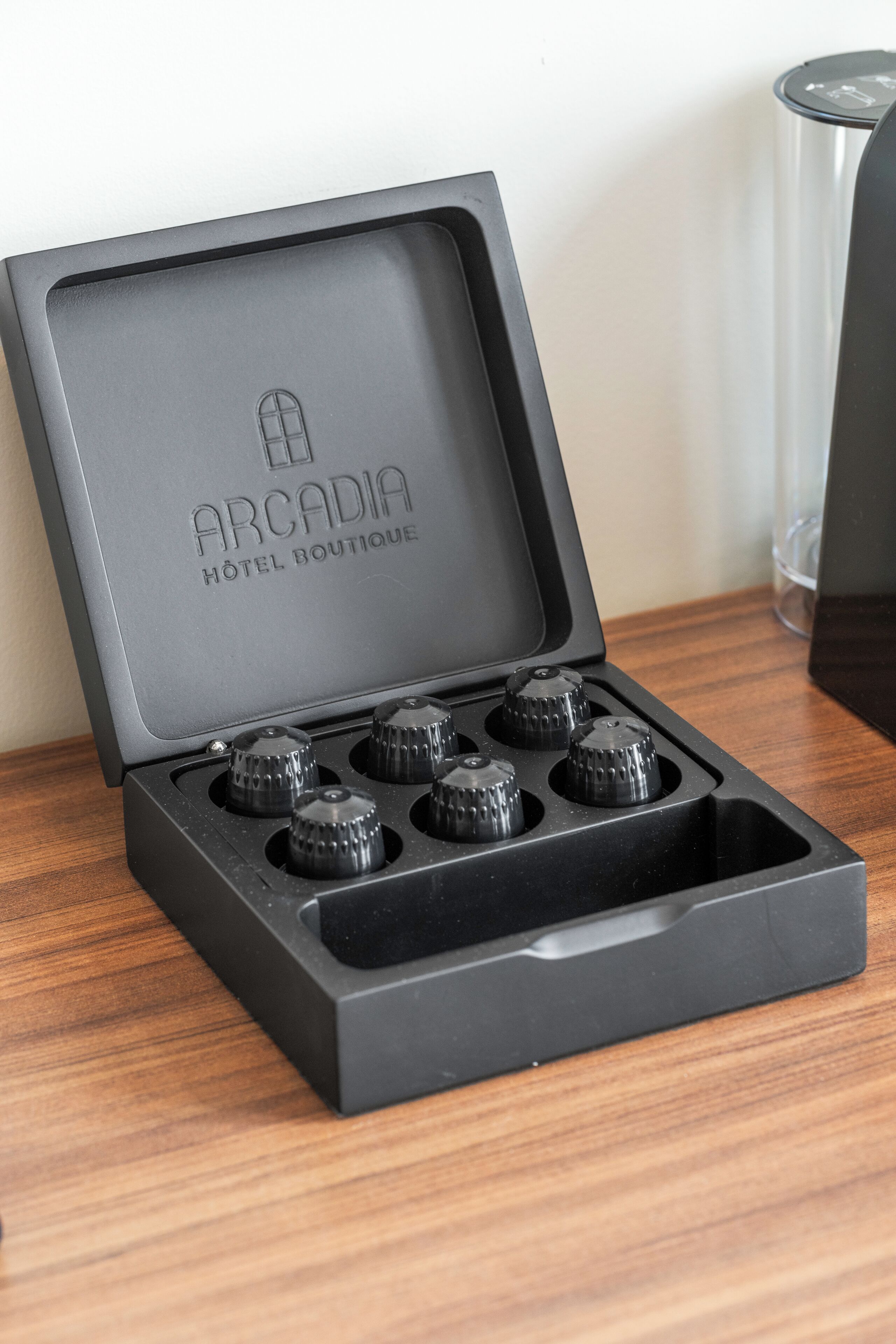 Una caja negra con el texto "ARCADIA HOTEL BOUTIQUE" y cuatro perillas en la tapa.