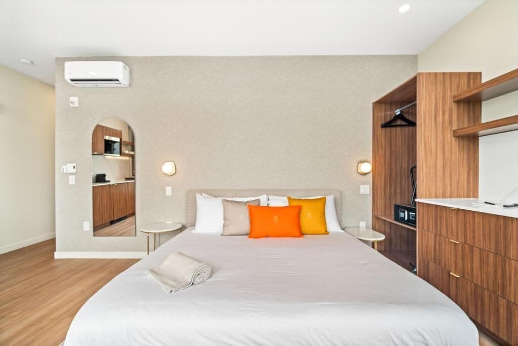 A hotel room with a large bed, a built-in wardrobe, a small bedside table, and a mirror.