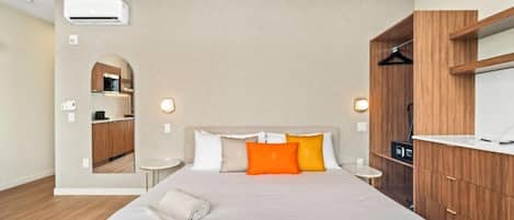 A hotel room with a large bed, a built-in wardrobe, a small bedside table, and a mirror.