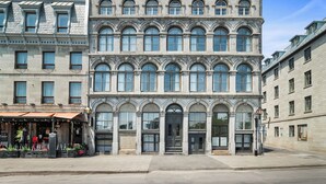 A multi-story building with a classical architectural style, featuring arched windows and a central entrance with a door and steps. - Arcadia Hotel Boutique (Montréal)