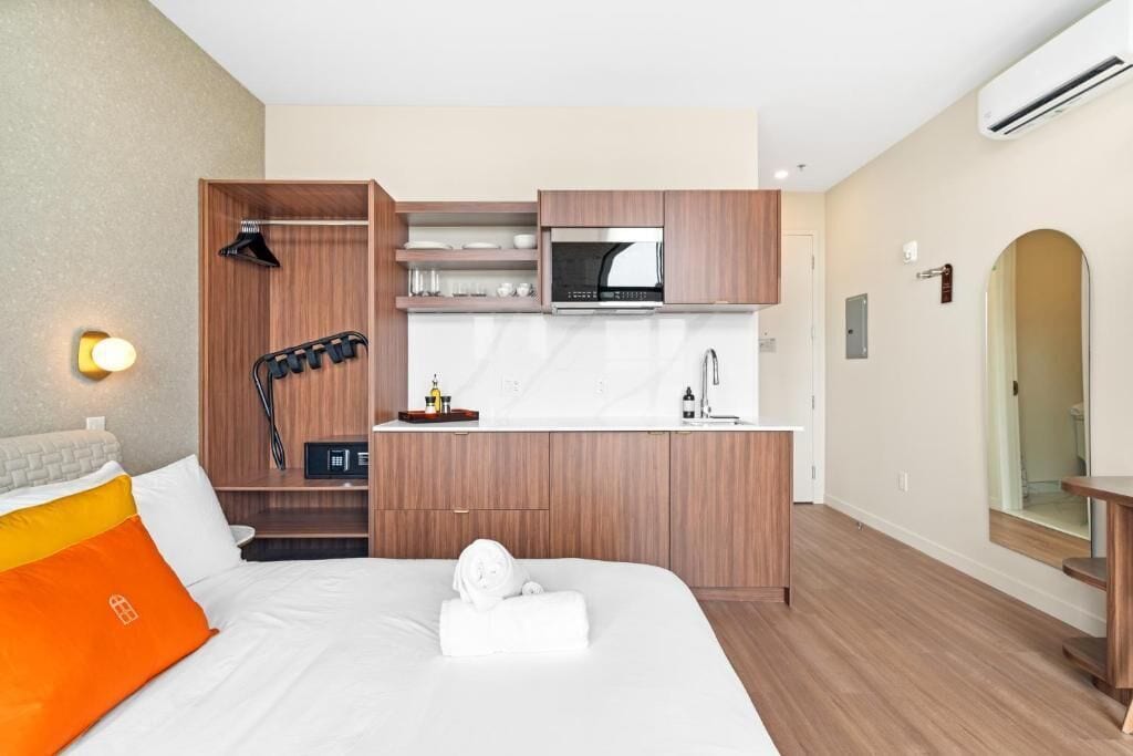 Une chambre d’hôtel comprenant un lit, une kitchenette intégrée, un four à micro-ondes et une petite salle de bain.