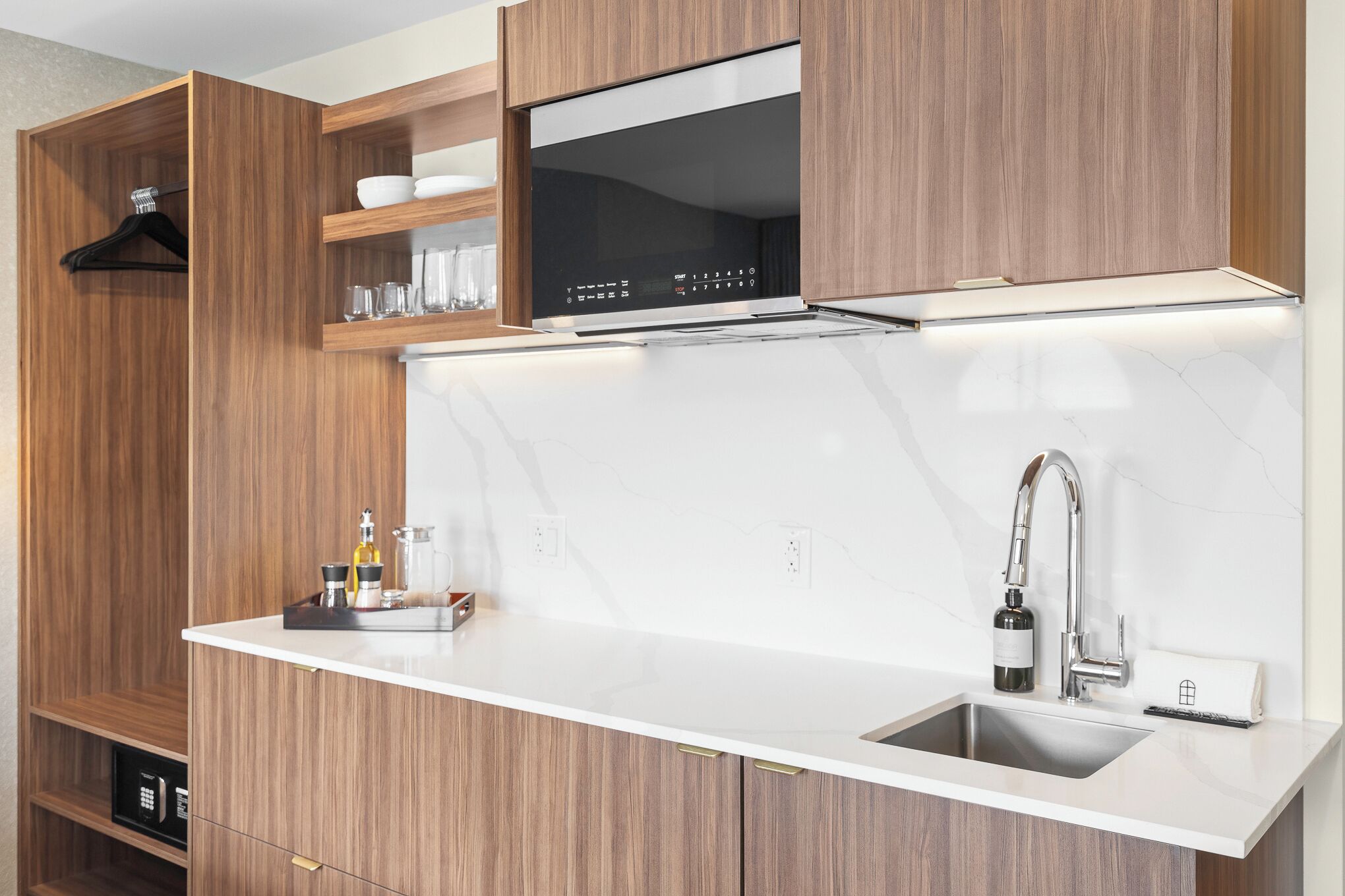 A modern kitchen with wooden cabinetry, a built-in microwave, and a stainless steel sink.