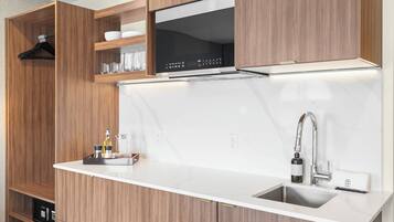 A modern kitchen with wooden cabinetry, a built-in microwave, and a stainless steel sink.