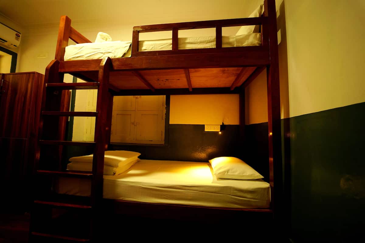 Un lit superposé avec une structure en bois, un lit simple en bas et une échelle sur le côté gauche.