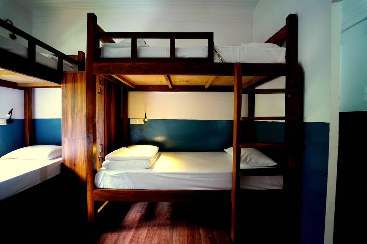 Une chambre avec un lit superposé en bois, un lit simple et une table de chevet.