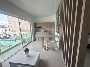Una cocina moderna con un ventanal grande, una zona de comedor con taburetes y vistas al exterior.