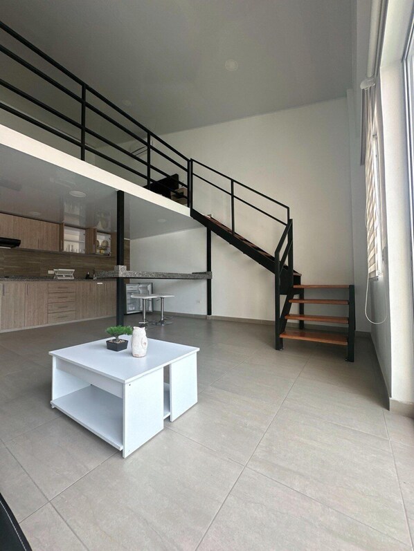 A modern apartment with a kitchen, a dining area, and a staircase.