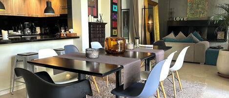 Una sala de estar moderna con comedor, que incluye un sofá, sillones, una mesa de centro y una chimenea.