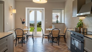 Een moderne keuken met een groot eiland, een eetgedeelte en uitzicht op de omgeving.