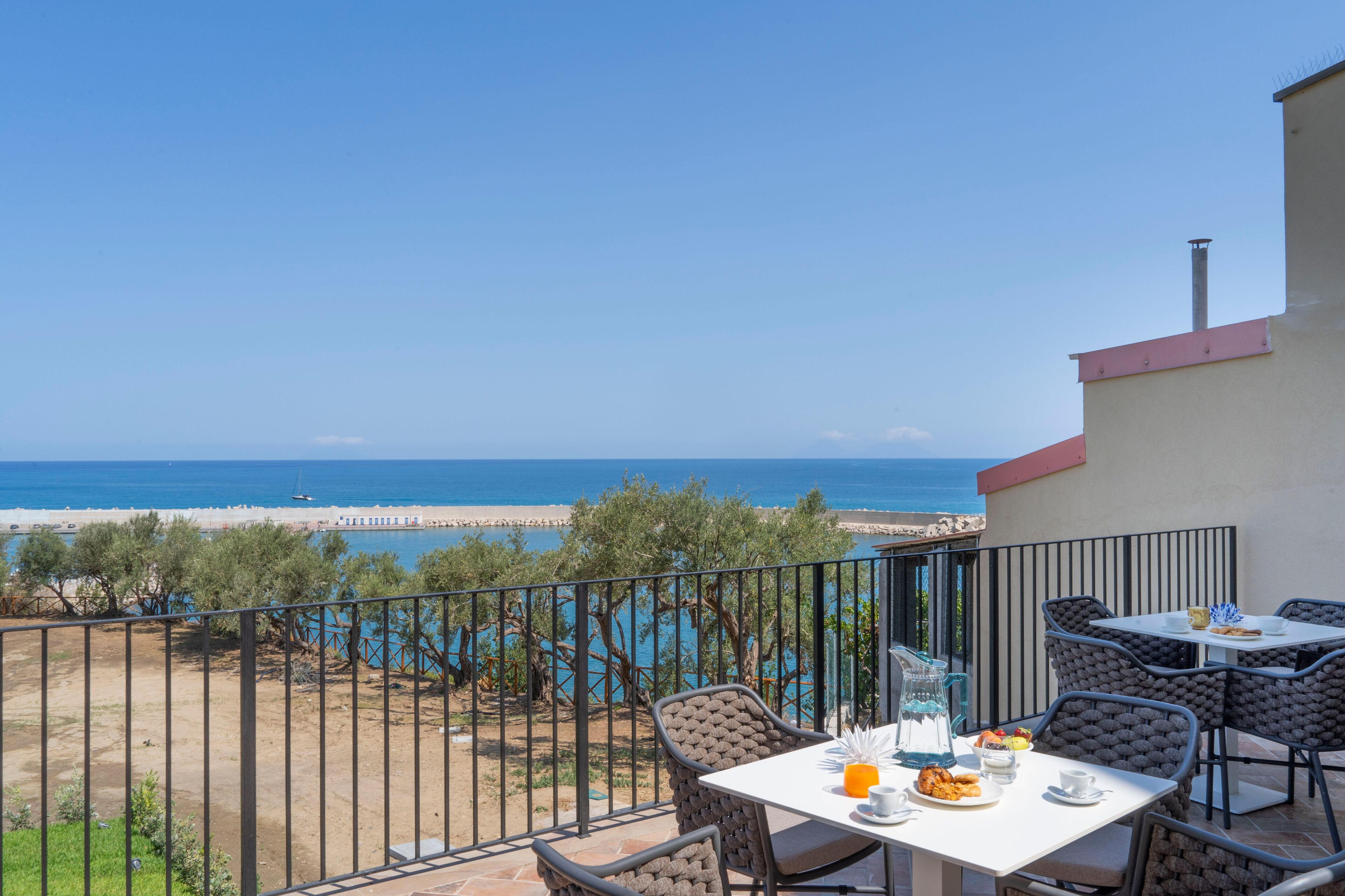 Ein Balkon mit einem Tisch für zwei Personen, mit Blick auf einen Strand und das Meer.