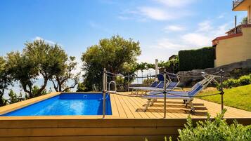 Una piscina con sillas de descanso y una terraza de madera.