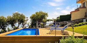 Une piscine avec des chaises longues et une terrasse en bois.