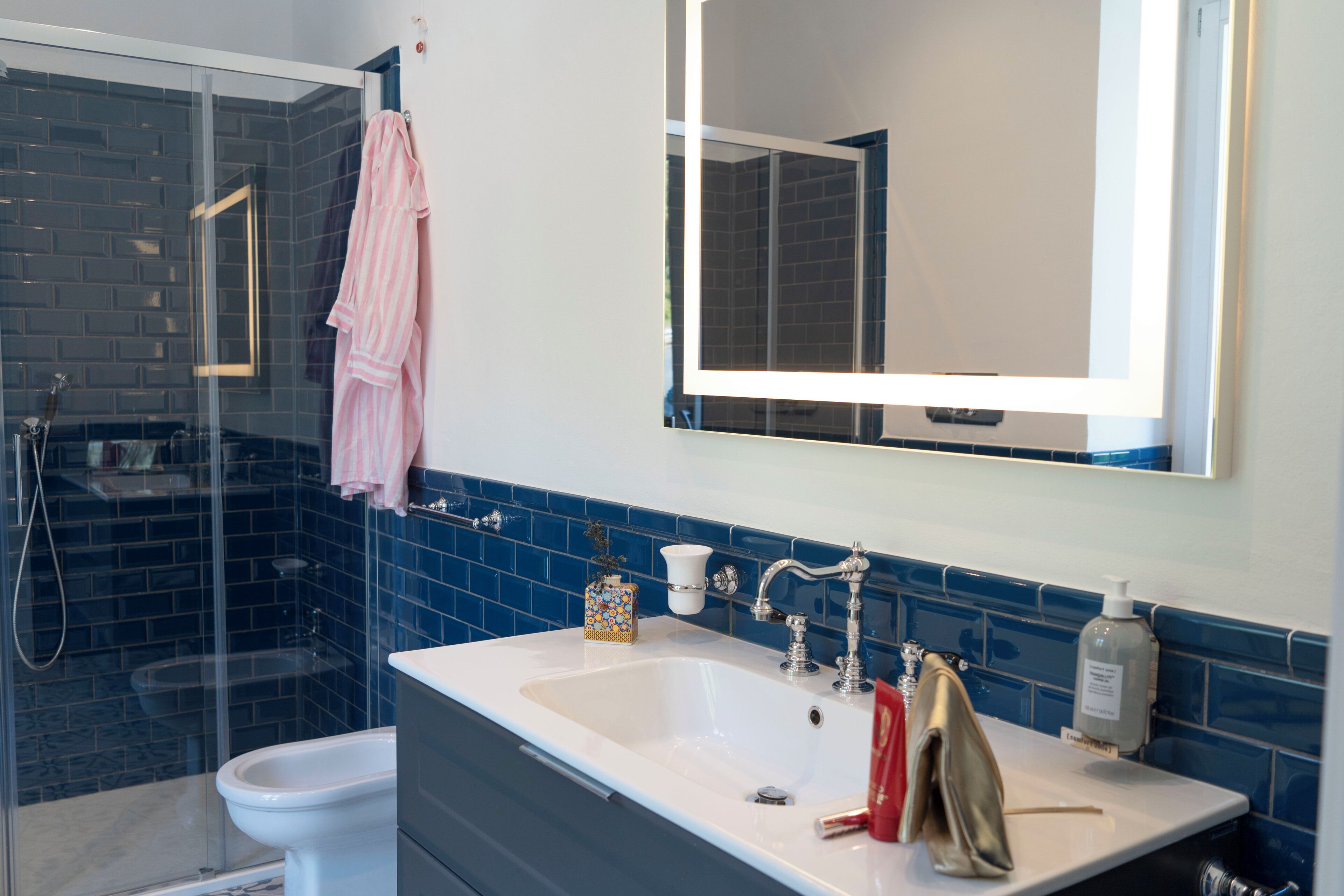 A bathroom with a glass shower enclosure, a white sink, and a large mirror.