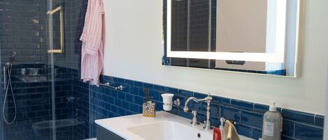 A bathroom with a glass shower enclosure, a white sink, and a large mirror.