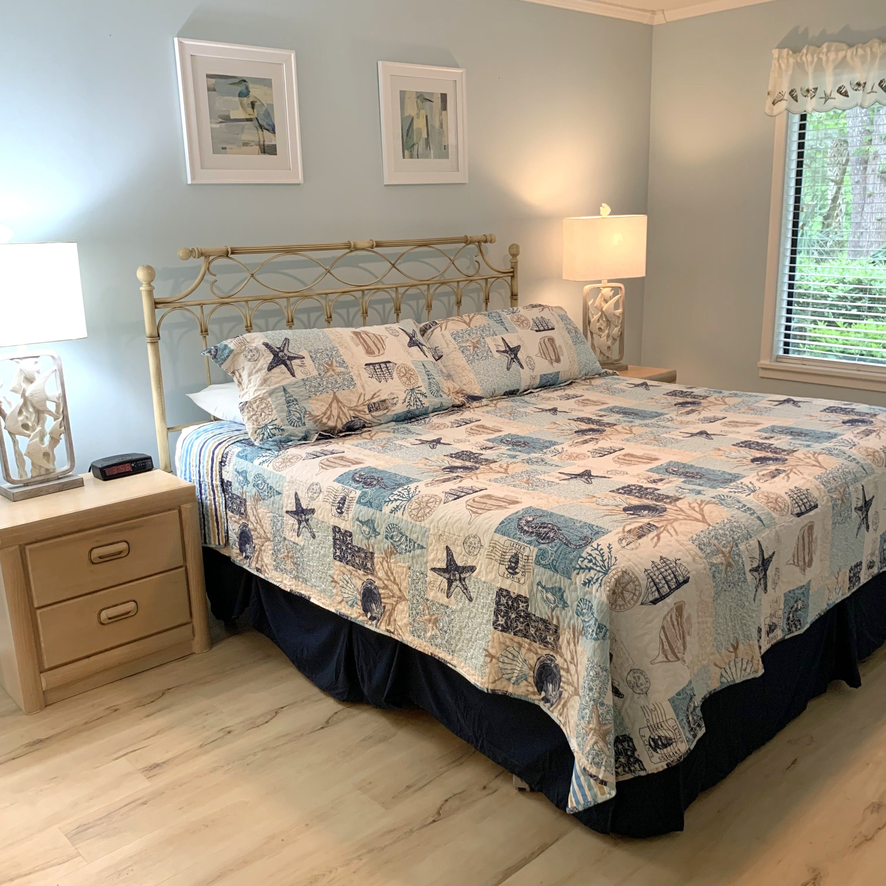A bedroom with a bed, bedside tables, a lamp, and artwork on the wall.