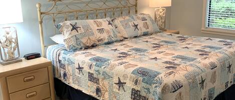 A bedroom with a bed, bedside tables, a lamp, and artwork on the wall.