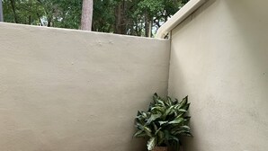 A patio area with a concrete floor, a potted plant, and a metal chair. - Beach Retreat 3BR Ground Floor Condo in Kingston Plantation! (Myrtle Beach)
