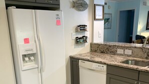 A kitchen with a white refrigerator, a dishwasher, granite countertops, and a window with a view. - Beach Retreat 3BR Ground Floor Condo in Kingston Plantation! (Myrtle Beach)