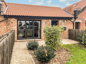 A brick house with a tiled roof, a glass door, a wooden fence, and a small garden. - Valentines Cottage - UK48509 (Kirk Hammerton, near York)