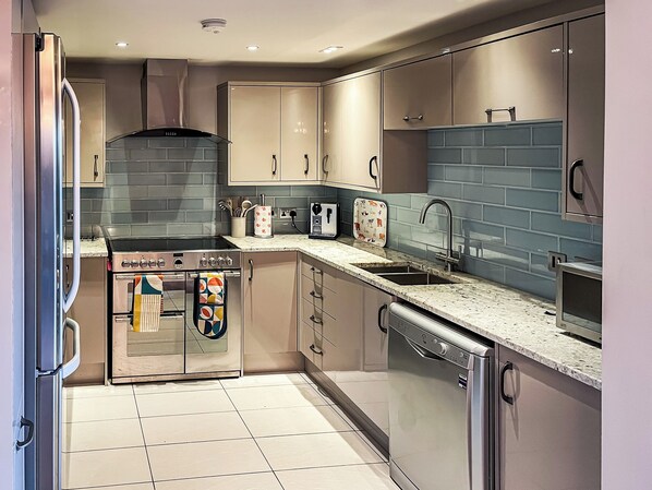 A modern kitchen with stainless steel appliances, a tiled backsplash, and a built-in oven.