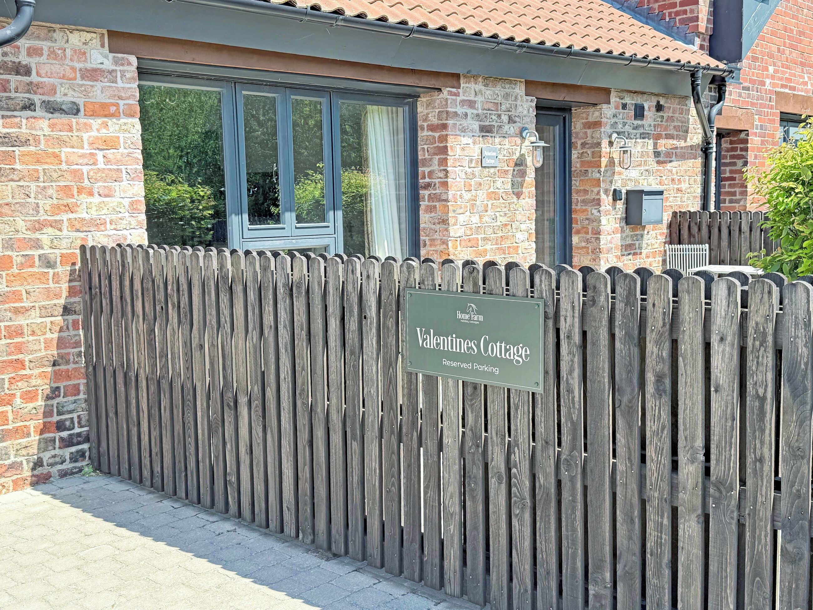 A wooden fence with a sign for 'Valentines Cottage' indicating reserved parking.