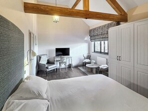 Un dormitorio con cama, escritorio, silla, mesita, radiador y armario.