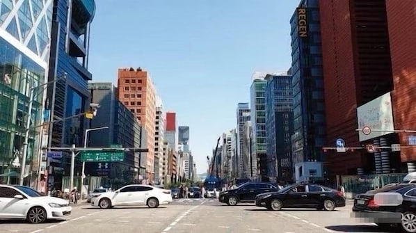 A city street with modern buildings, cars, and a clear sky.