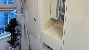 Ett modernt badrum med en stor spegel, en tvättställsmöbel och en krukväxt.