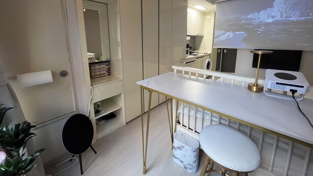 Ett modernt kök med en bardisk, en tvättmaskin och en projektorduk som visar ett snötäckt landskap.