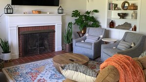 A living room with a fireplace, a television, a sofa, a coffee table, and a bookshelf.