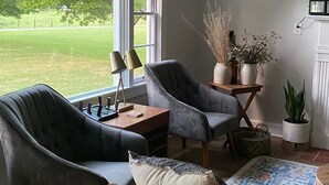 A living room with a large window, two armchairs, a sofa, a coffee table, and a rug.