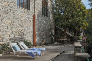 A stone building with lounge chairs and a table outside. - Villa Eugenia suite (Carate Urio)