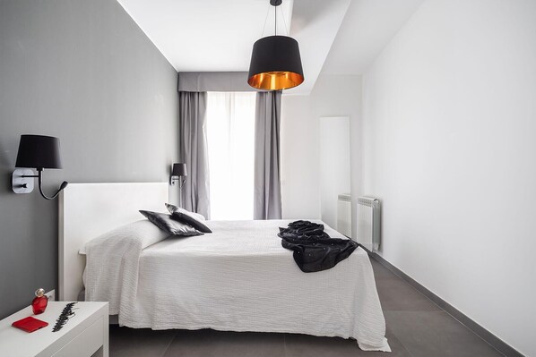 A modern bedroom with a bed, a bedside table, a lamp, and a radiator.