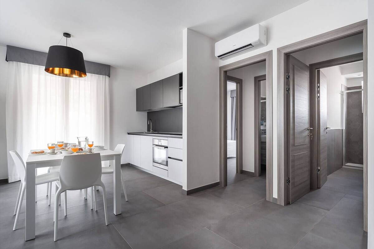 Una cocina moderna con armarios blancos, horno integrado y equipo de aire acondicionado.