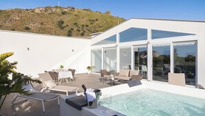A modern outdoor pool area with a glass-enclosed patio, lounge chairs, and a dining table. - Design Apartments D'Orlando (Capo d'Orlando)